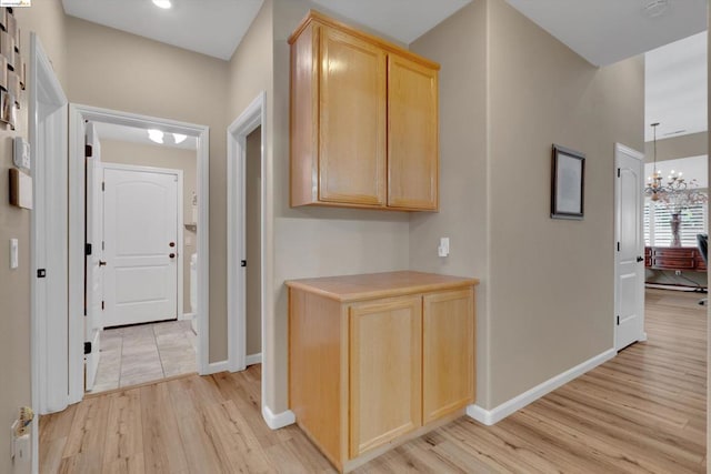 hallway featuring an inviting chandelier and light hardwood / wood-style floors