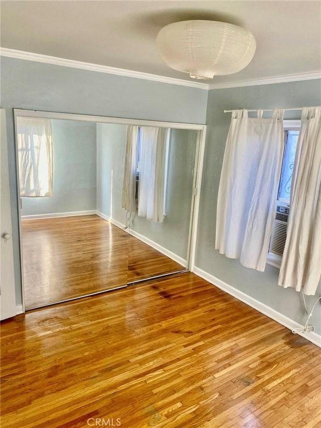 unfurnished bedroom featuring a closet, ornamental molding, hardwood / wood-style flooring, and multiple windows