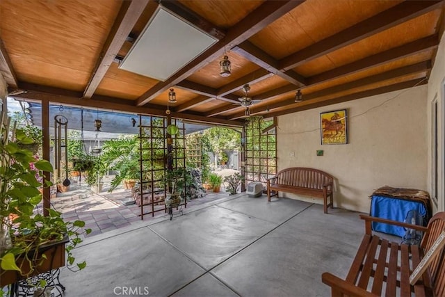 unfurnished sunroom with ceiling fan and beam ceiling