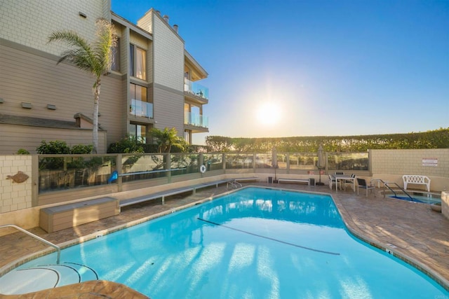 pool at dusk with a patio area