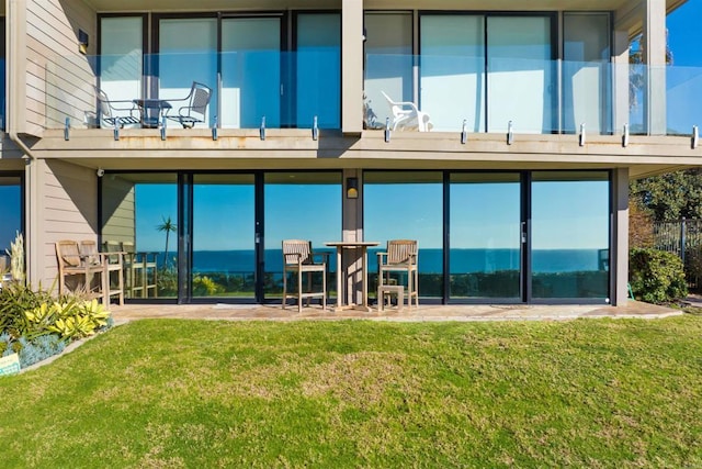 rear view of house featuring a lawn and a balcony