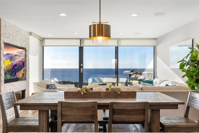 dining space with a stone fireplace, a wealth of natural light, hardwood / wood-style floors, and a water view