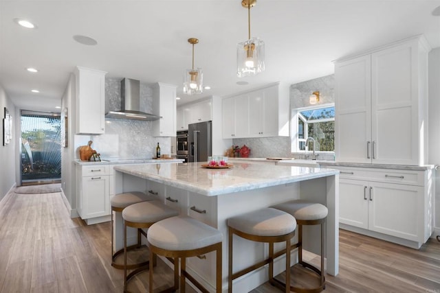 kitchen featuring decorative backsplash, wall chimney exhaust hood, stainless steel appliances, and a center island