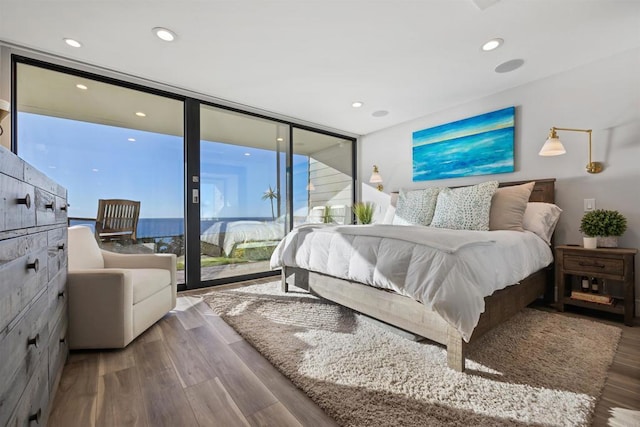 bedroom with expansive windows, hardwood / wood-style flooring, and access to outside