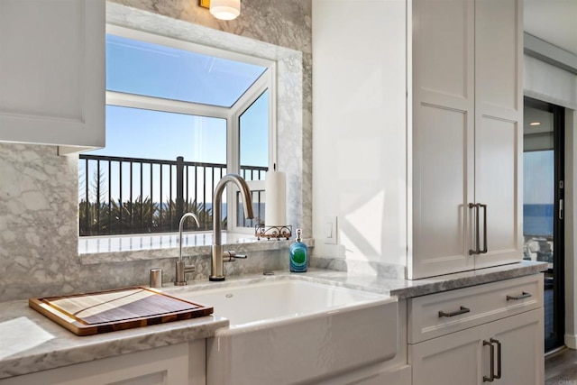 kitchen with light stone counters, sink, decorative backsplash, and white cabinets