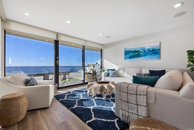 living room with hardwood / wood-style flooring, a wall of windows, and a water view