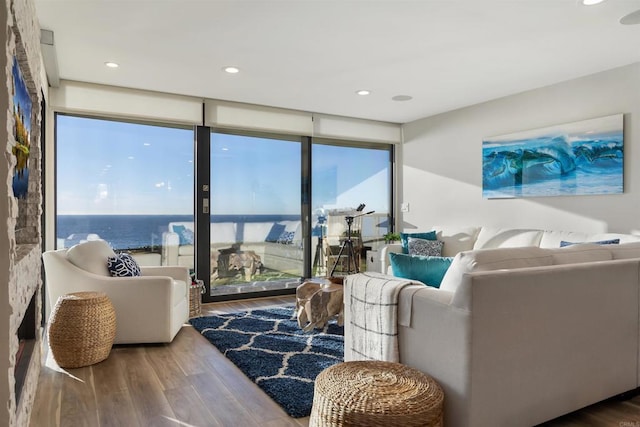 living room featuring floor to ceiling windows, hardwood / wood-style flooring, and a water view