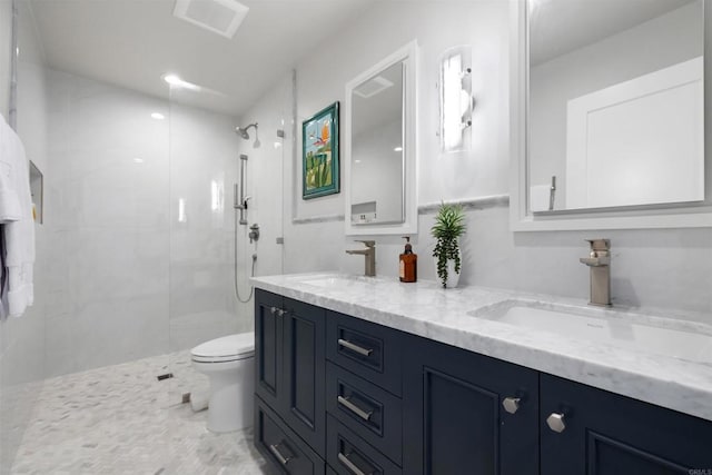 bathroom featuring toilet, vanity, and a tile shower