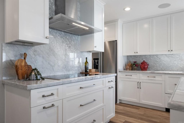 kitchen with white cabinetry, black electric stovetop, backsplash, wall chimney range hood, and light hardwood / wood-style flooring