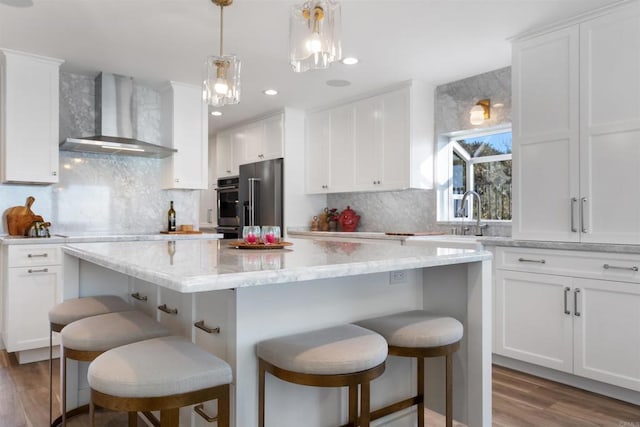 kitchen with tasteful backsplash, appliances with stainless steel finishes, wall chimney exhaust hood, and a center island