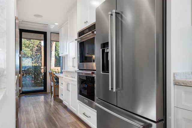 kitchen with wood-type flooring, white cabinetry, and stainless steel appliances