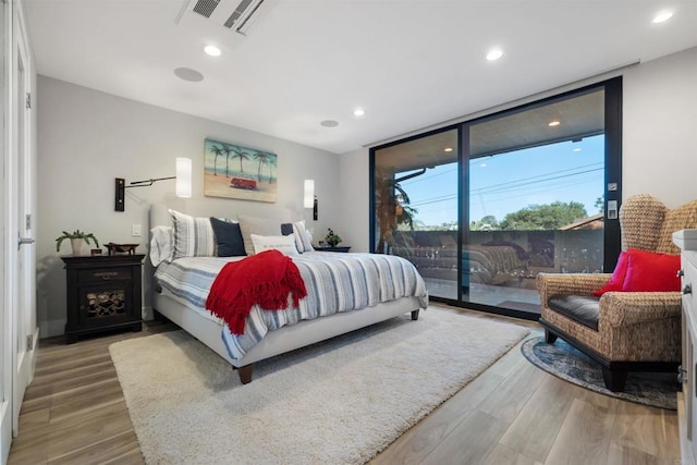 bedroom with access to outside, floor to ceiling windows, and hardwood / wood-style floors