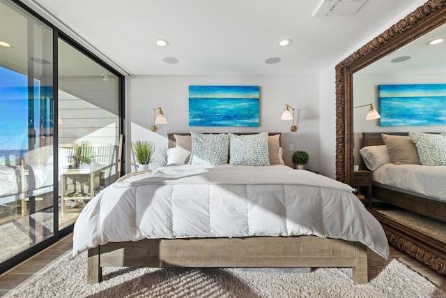 bedroom with expansive windows and hardwood / wood-style floors