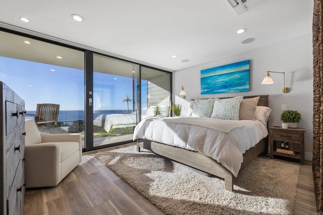 bedroom with floor to ceiling windows, multiple windows, hardwood / wood-style floors, and access to outside