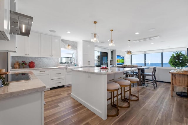 kitchen with a kitchen island, white cabinetry, light stone countertops, a water view, and black electric cooktop