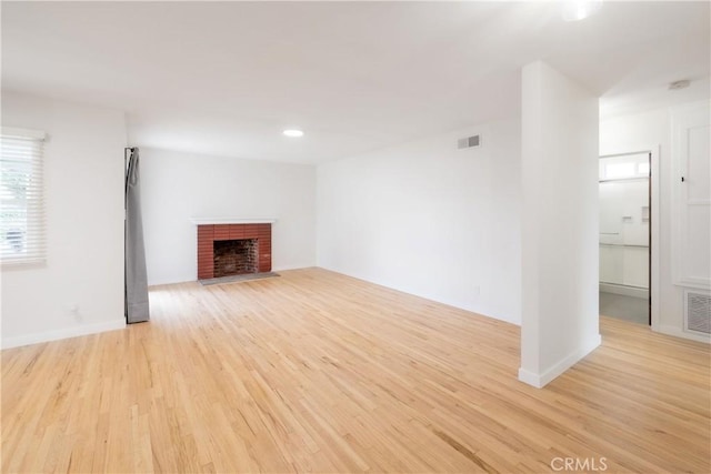 unfurnished living room with a brick fireplace and light wood-type flooring