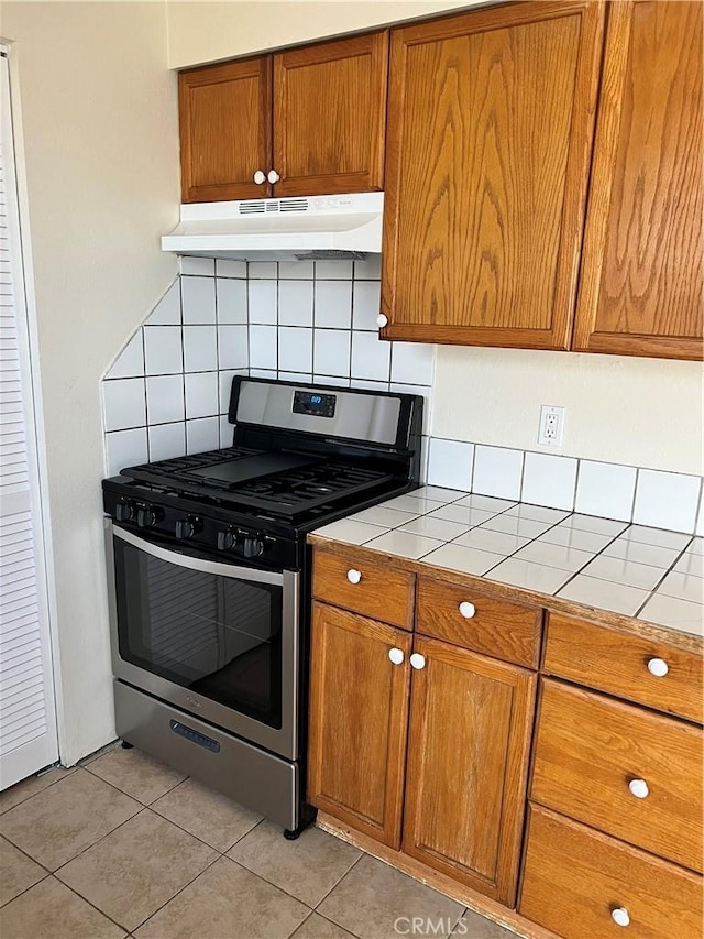 kitchen featuring light tile patterned floors, backsplash, stainless steel range with gas cooktop, and tile countertops