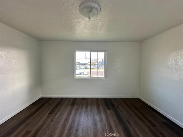 spare room with a textured ceiling and dark hardwood / wood-style floors