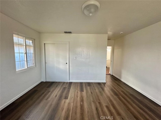 unfurnished bedroom featuring dark wood-type flooring and a closet