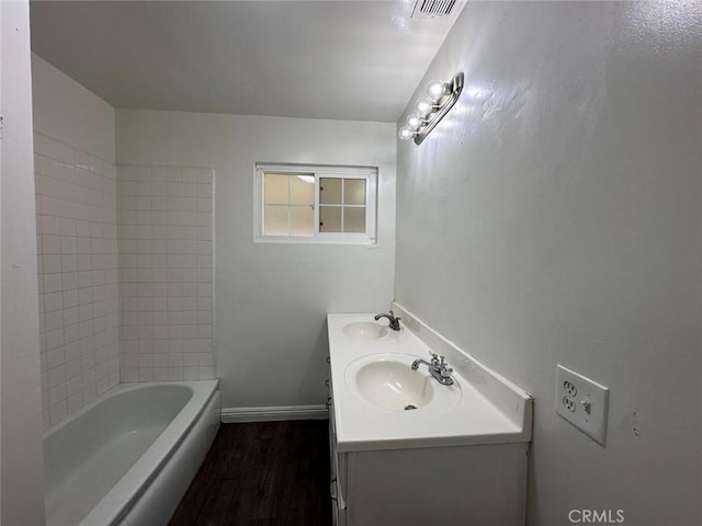 bathroom with vanity, tiled shower / bath, and hardwood / wood-style floors