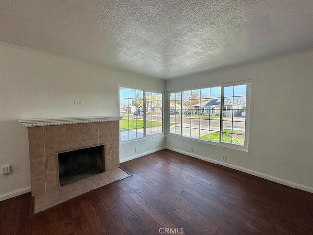 unfurnished living room with dark wood-type flooring, a tile fireplace, and a textured ceiling