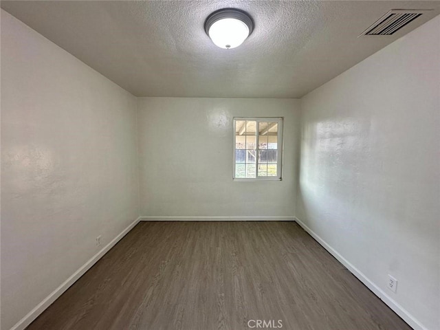 unfurnished room featuring a textured ceiling and dark hardwood / wood-style flooring