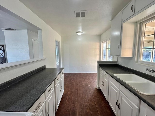 kitchen with dark wood-type flooring, sink, and white cabinetry