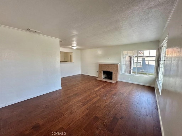 unfurnished living room featuring a textured ceiling, dark wood-type flooring, and a tiled fireplace