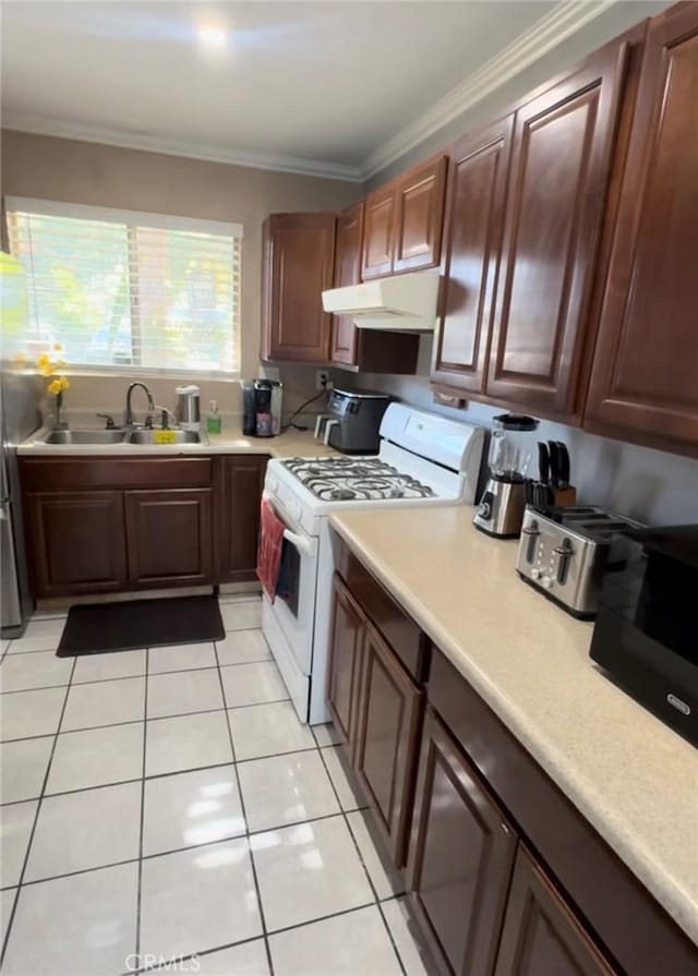 kitchen with white range, ornamental molding, sink, and light tile patterned floors