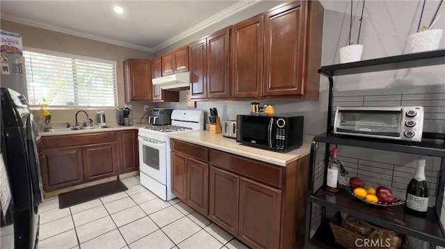 kitchen featuring light countertops, a sink, black microwave, under cabinet range hood, and white gas range oven