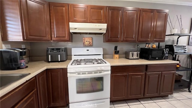 kitchen with a toaster, light countertops, white gas stove, under cabinet range hood, and black microwave