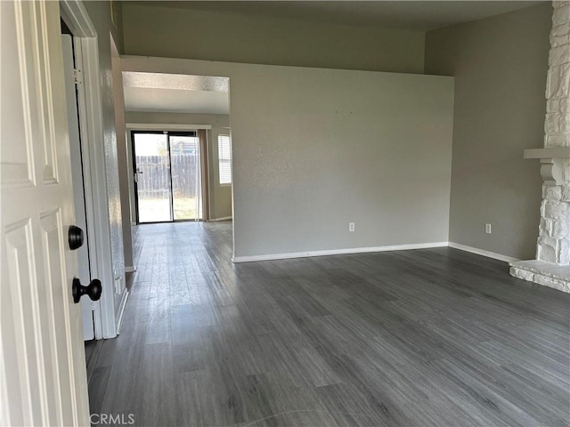 empty room featuring dark hardwood / wood-style flooring and a stone fireplace