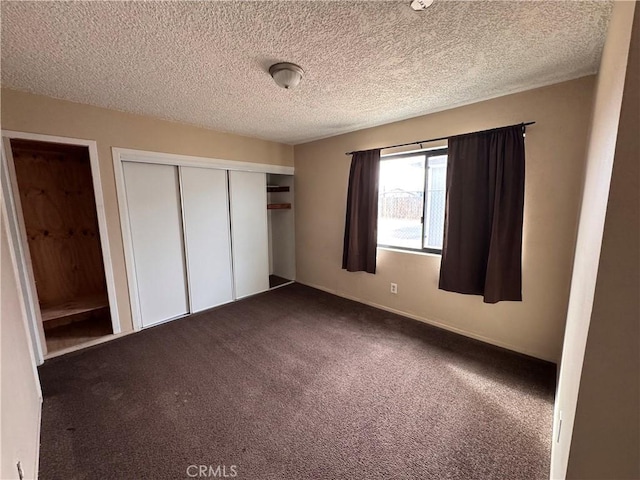 unfurnished bedroom featuring a textured ceiling, a closet, and dark colored carpet