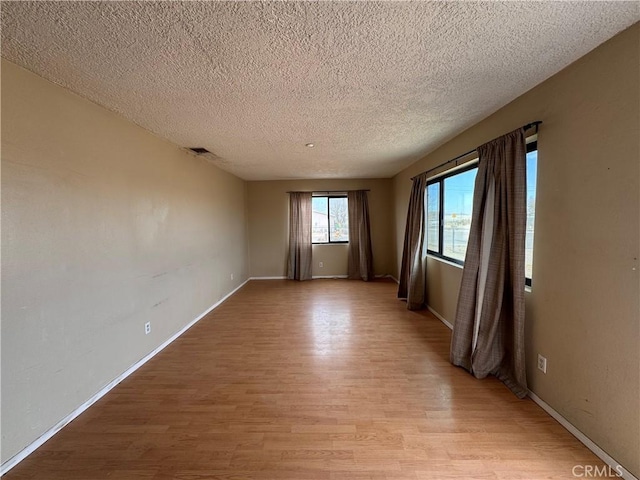 spare room featuring a textured ceiling and light hardwood / wood-style flooring