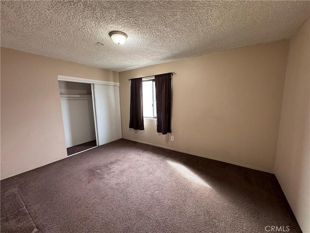 unfurnished bedroom featuring a closet, dark carpet, and a textured ceiling