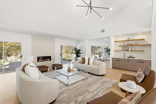 living room with a fireplace, light hardwood / wood-style floors, a notable chandelier, high vaulted ceiling, and wooden ceiling