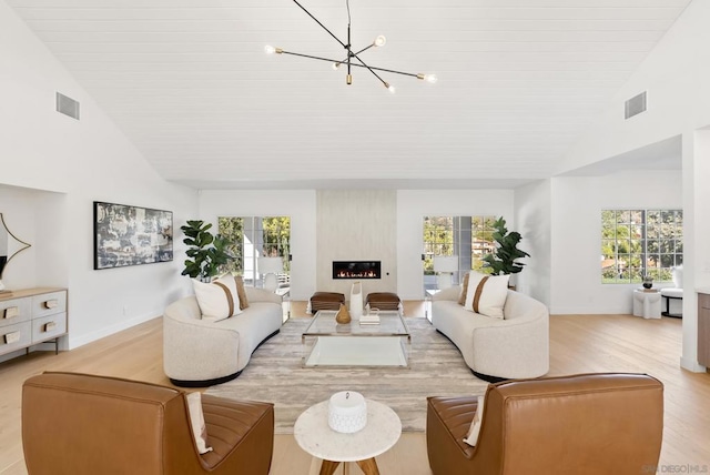 living room with a large fireplace, light hardwood / wood-style flooring, and a wealth of natural light