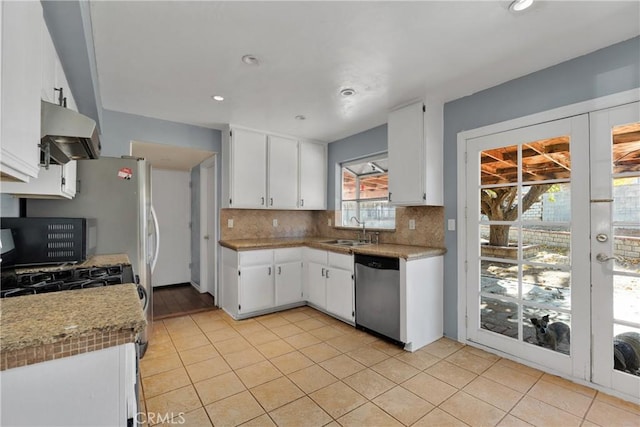 kitchen featuring stainless steel dishwasher, exhaust hood, sink, and white cabinetry