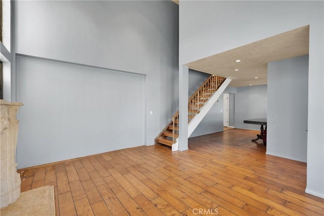 unfurnished living room featuring light wood-type flooring and a high ceiling