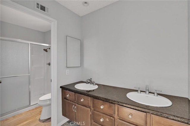 bathroom with a shower with shower door, hardwood / wood-style floors, toilet, and vanity