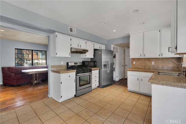 kitchen featuring backsplash, sink, light tile patterned flooring, stainless steel appliances, and white cabinets