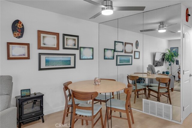 dining space featuring light hardwood / wood-style floors and a wood stove