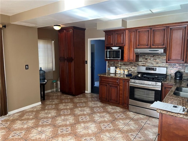 kitchen featuring appliances with stainless steel finishes, backsplash, dark stone counters, and sink