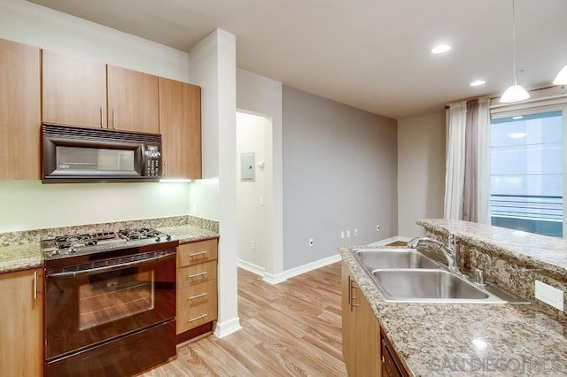 kitchen featuring light hardwood / wood-style floors, black appliances, sink, hanging light fixtures, and light stone countertops