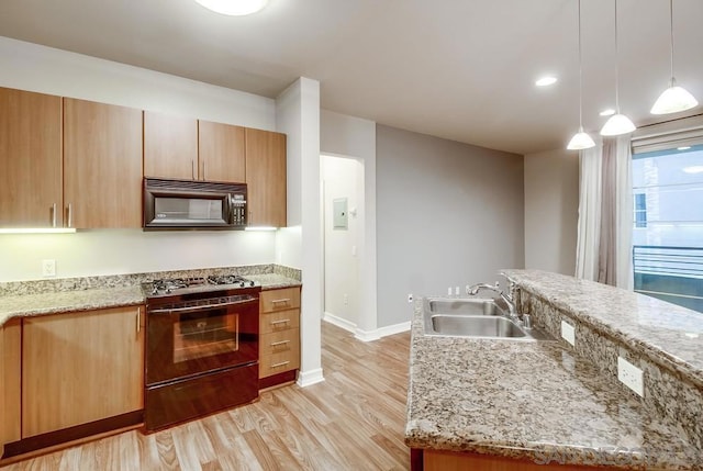 kitchen with range with gas cooktop, light hardwood / wood-style floors, pendant lighting, light stone counters, and sink