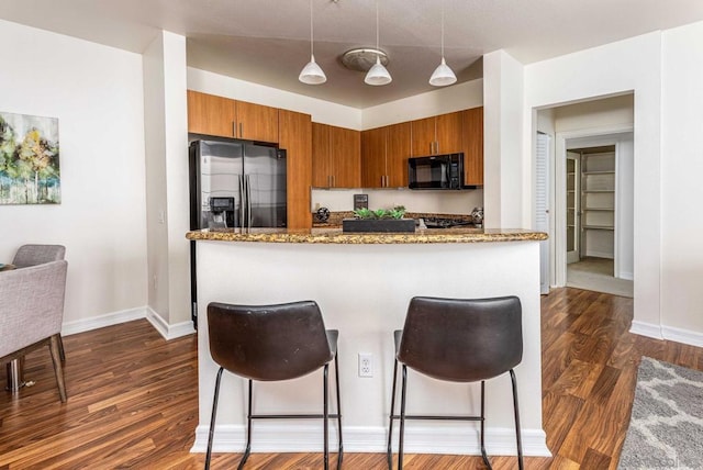 kitchen with stainless steel fridge with ice dispenser, a kitchen bar, kitchen peninsula, dark hardwood / wood-style floors, and decorative light fixtures