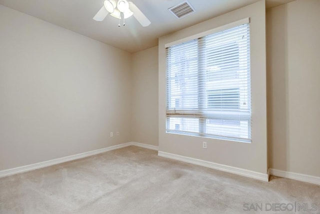 spare room with ceiling fan, light colored carpet, and plenty of natural light