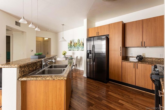 kitchen featuring sink, hanging light fixtures, stainless steel fridge, and a kitchen island with sink