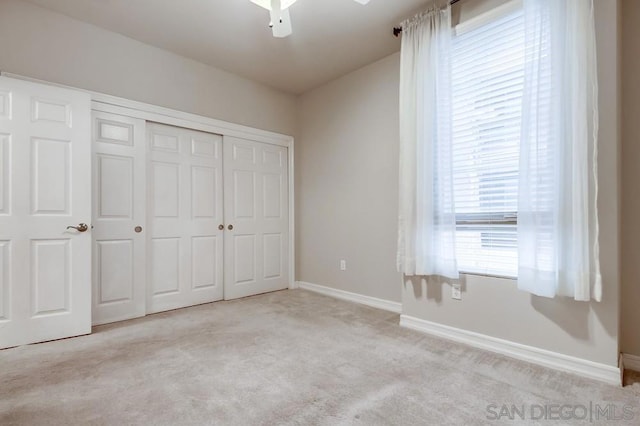 unfurnished bedroom with ceiling fan, a closet, and light colored carpet