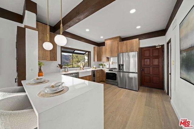 kitchen featuring pendant lighting, kitchen peninsula, beamed ceiling, light hardwood / wood-style flooring, and stainless steel appliances